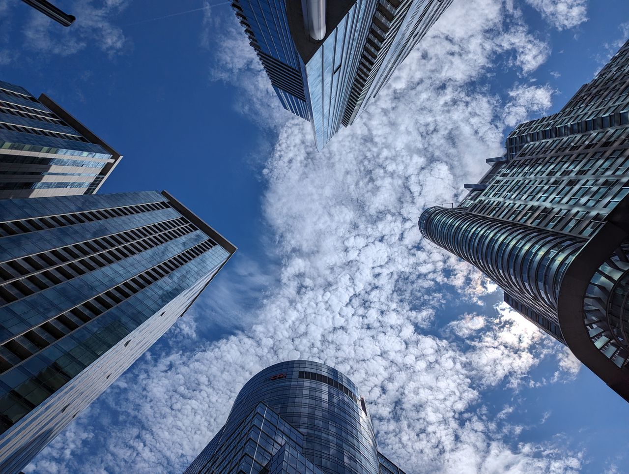 Looking up at modern skyscrapers under a blue sky with dramatic clouds.